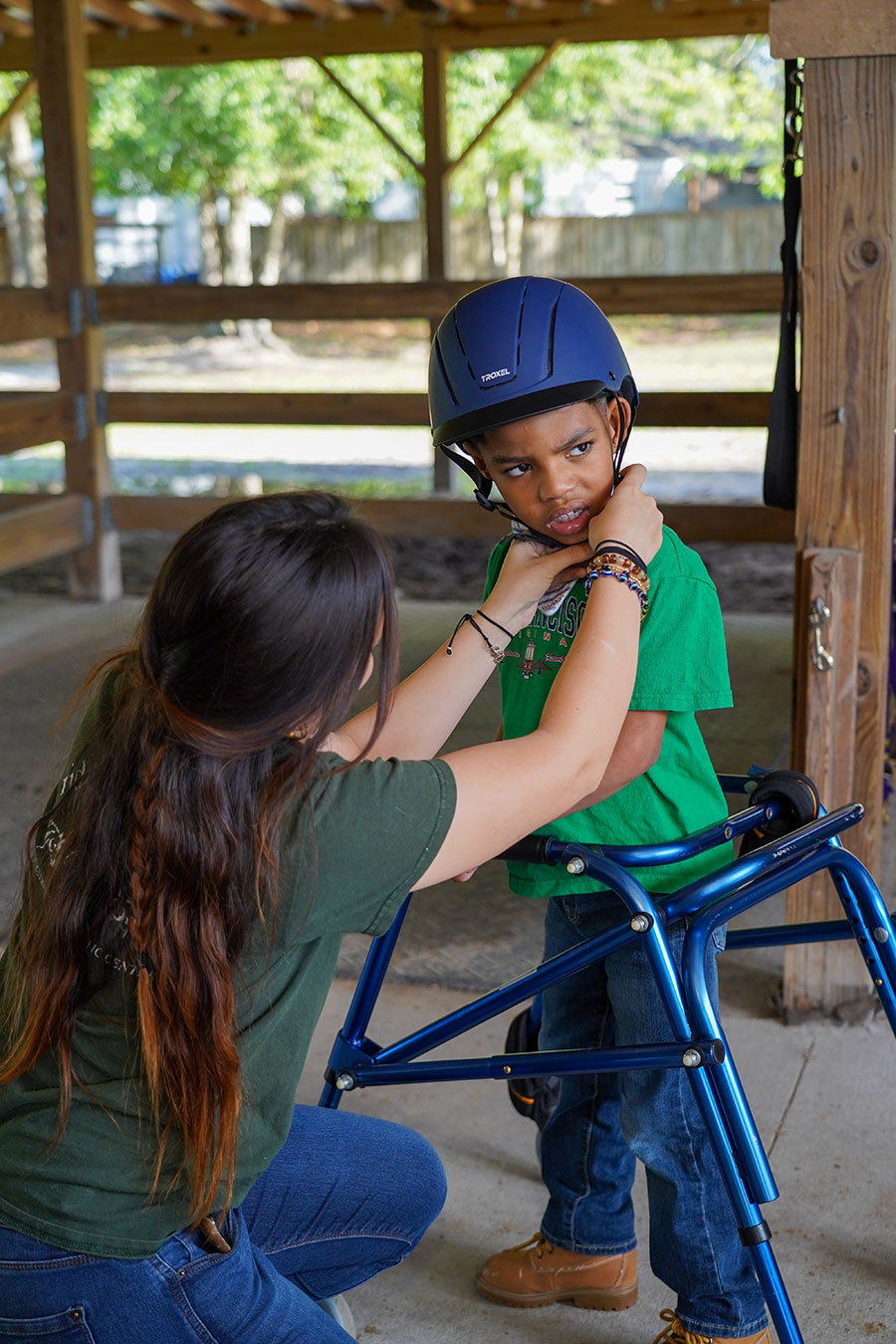picture of Jaxon, a young rider being assisted with a helmet