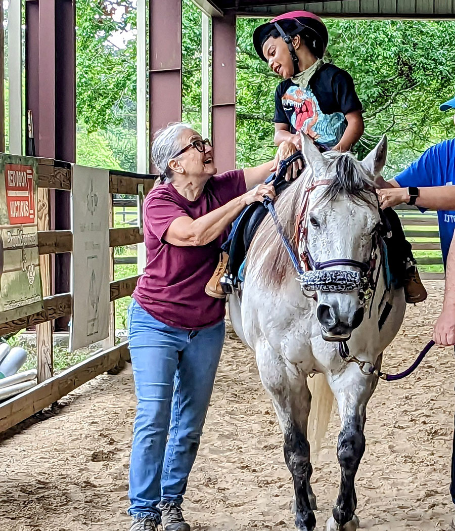 photo of a volunteer walking along side a mounted rider at Faith Equestrian Therapeutic Center